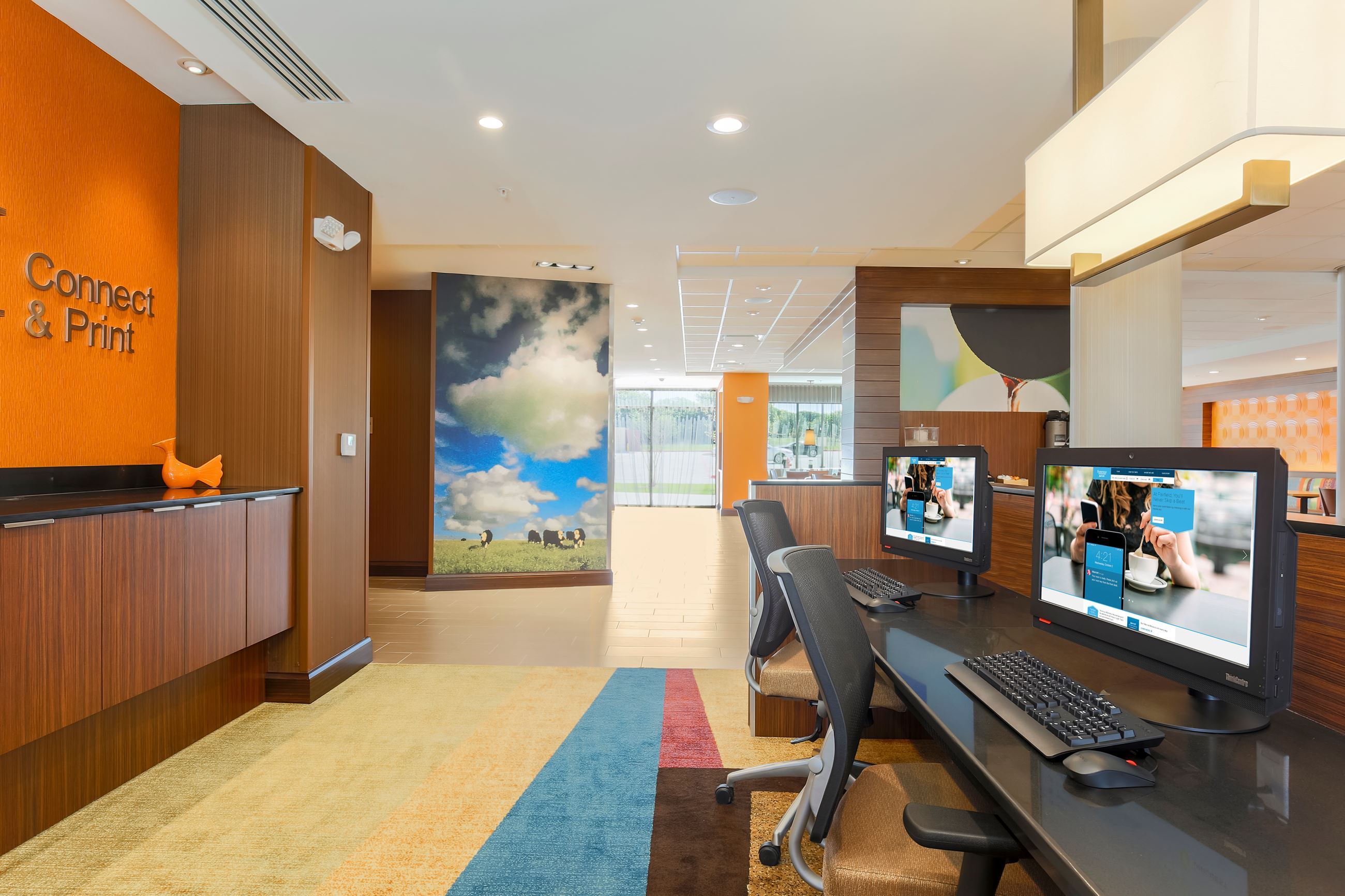 Modern hotel view from behind the front desk counter with two computers on a multi colored rug