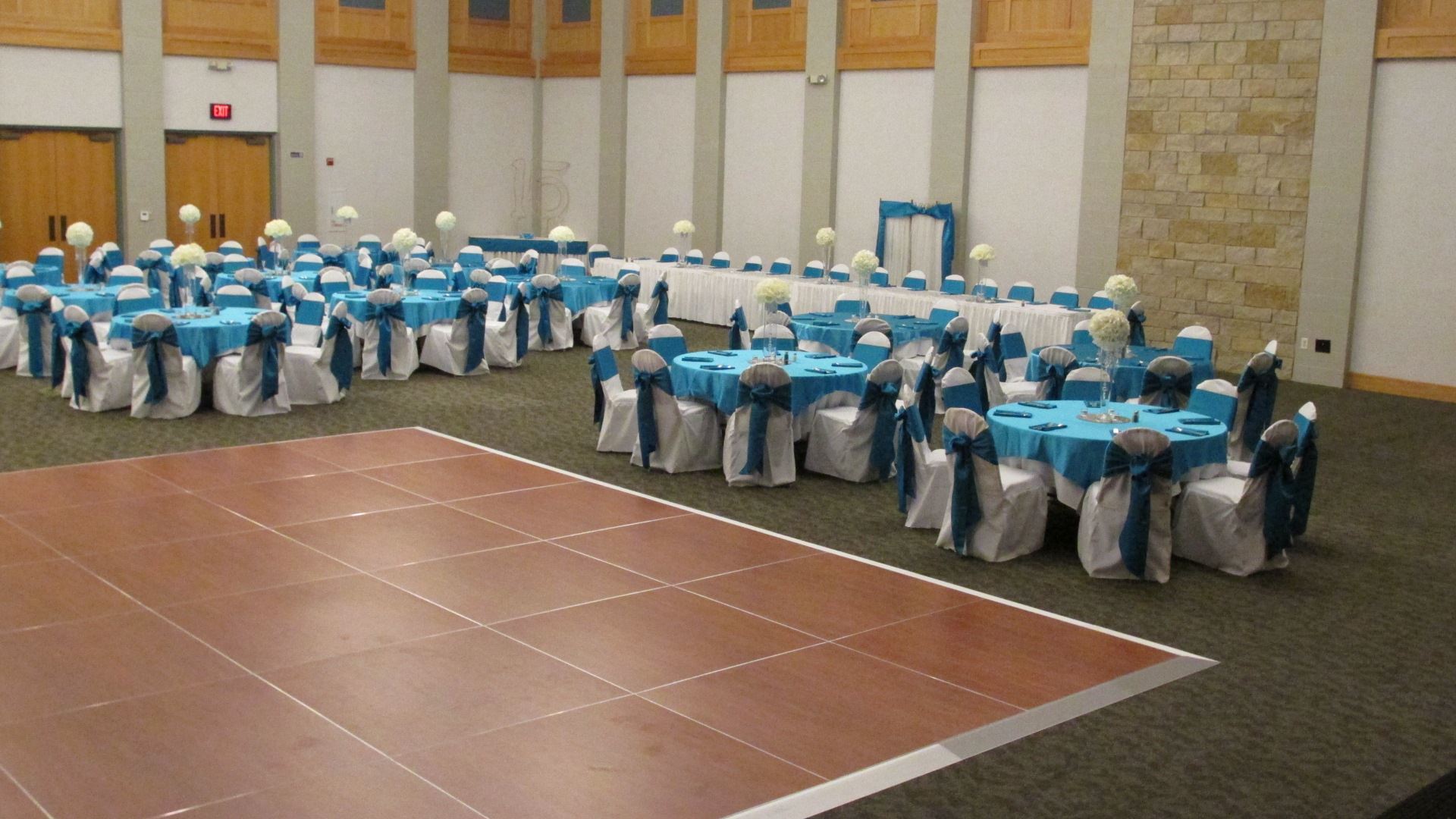 Turquoise and white wedding reception with table settings of turquoise table cloths with a dance flo