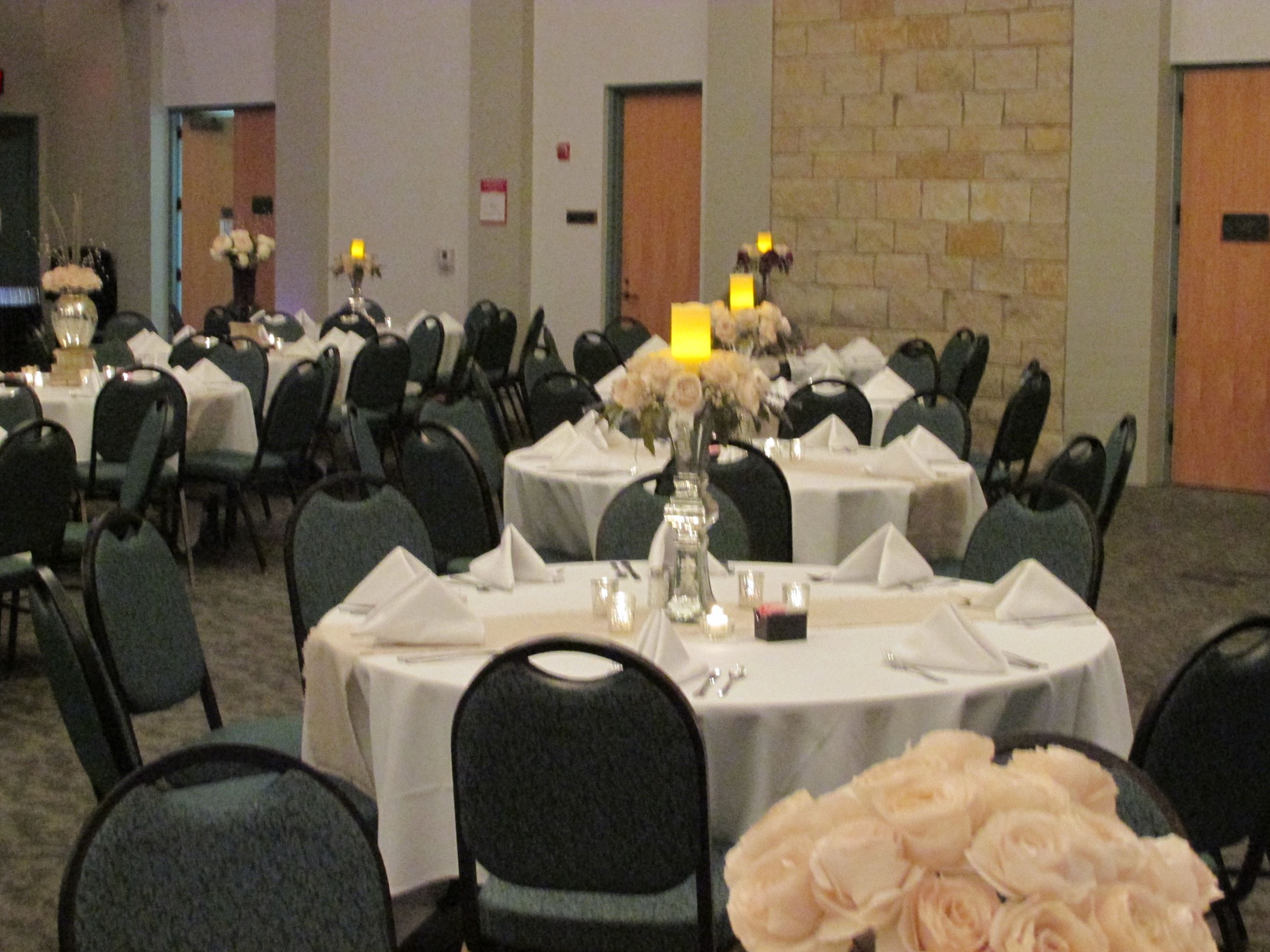 Winter white wedding reception with table settings of white table cloths and peach runners and rose 